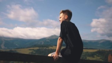 Çocuk rüzgarlı bir günde dağlara bakıyor.