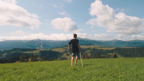 Jongen rent in weide en bewondert bergen — Stockvideo