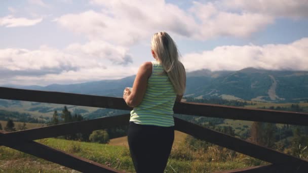 Mujer con bebida caliente descansando en las tierras altas — Vídeos de Stock