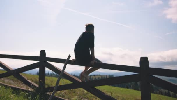 山の柵の上に座っている少年 — ストック動画