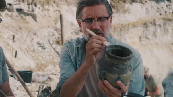 동료 근처에서 골동품 꽃병을 청소하는 유명 한 고고학자 — 비디오