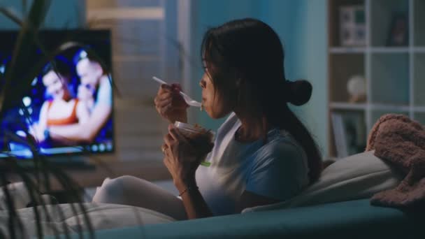 Женщина ест перед телевизором — стоковое видео