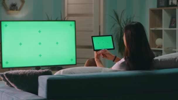 Жінка переглядає планшет і дивиться телевізор — стокове відео