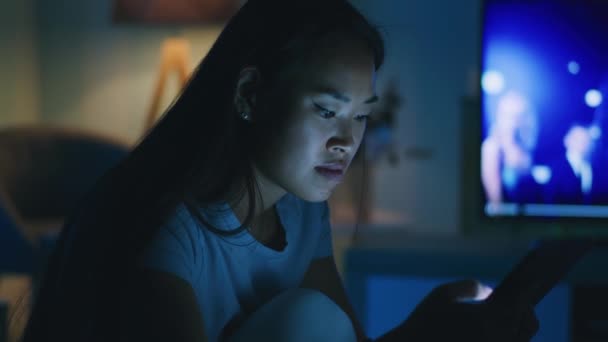 Vrouw browsen tablet in de buurt van TV in de avond — Stockvideo