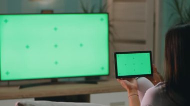 Anonim anne TV 'nin yanındaki tablete göz atıyor