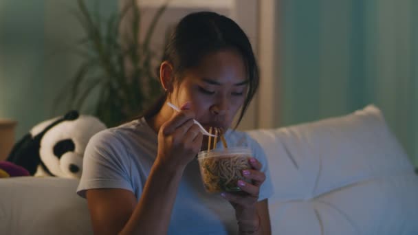 Mujer comiendo en el sofá por la noche — Vídeo de stock