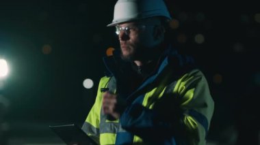 Erkek işçi tablet kullanıyor ve radyoda konuşuyor.
