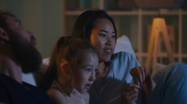 Ailesiyle televizyon izleyen Asyalı kadın.