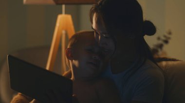 Anne ve oğul gece tablet kullanıyor.