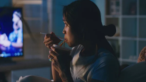 Asijské žena jíst a dívat se na televizi — Stock fotografie