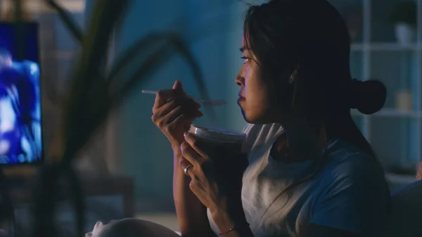 Asijské žena jíst a dívat se na televizi — Stock fotografie