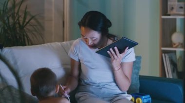 Asyalı anne tablette yiyor ve konuşuyor.