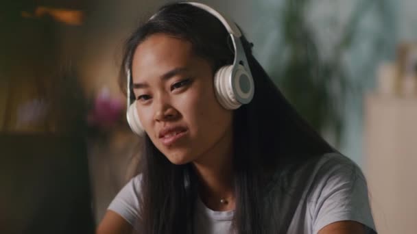 Aziatische vrouw luisteren naar muziek tijdens remote werk — Stockvideo