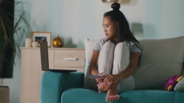 Asian female doing pedicure near laptop — Stock Video