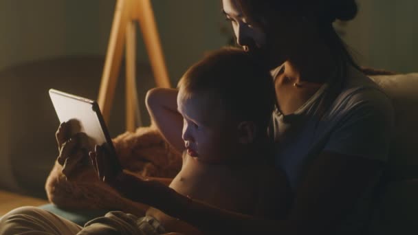 Moeder en zoon kijken video in de avond — Stockvideo
