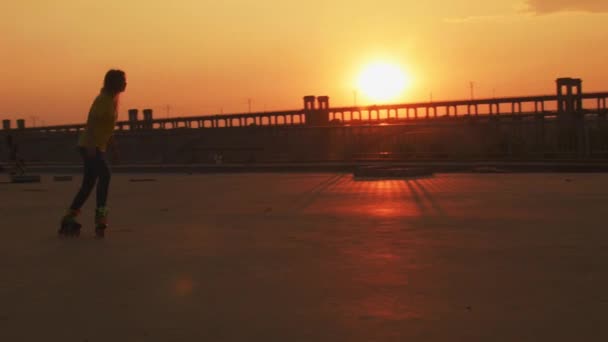 Девушка катается на коньках по мосту на закате — стоковое видео