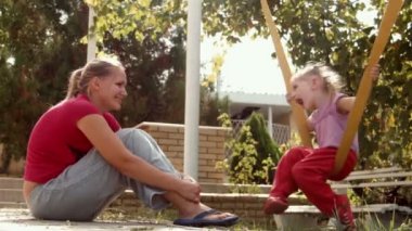 Anne kızı salıncakta alır.