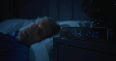 Karanlık Yatak Odasında Huzursuz Adam, Sabah 2 'de Parlayan Dijital Saat. Yaşlanma korkusuyla yüzleşen Uykusuz Adam. Uykusuzluk, Yalnızlık, Uykusuz Gece 'deki Derin Varoluşsal Düşünceler.