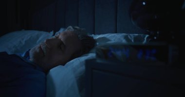 Karanlık Yatak Odasında Huzursuz Adam, Sabah 2 'de Parlayan Dijital Saat. Yaşlanma korkusuyla yüzleşen Uykusuz Adam. Uykusuzluk, Yalnızlık, Uykusuz Gece 'deki Derin Varoluşsal Düşünceler.