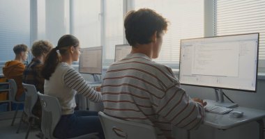 Öğrencilerin Bilgisayar Üzerine Kodladığı Üniversite Sınıfı. Çizgili Gömlekli Genç Adam Oyun Geliştirme Projesi için Ekrana Odaklandı. Dijital Eğitim kavramı, takım çalışması. Doli Vuruşu