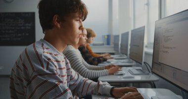 Parlak Sınıftaki Bilgisayar 'da Erkek Öğrenci Programı. IT Sınıfında Yazılım Çalışan ve Oyun Geliştirme Projeleri Yaratan Gençler Grubu. Takım çalışması, Teknoloji Eğitimi. Doli Vuruşu.