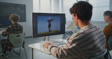 Çizgili Tişörtlü Öğrenci Modern Sınıfta Bilgisayarda 3D Animasyon Oluşturdu. Genç adam, 3D Modelleme Yazılımıyla Bilgisayar ekranına odaklanmış. Yaratıcı Öğrenme, Tasarım Geleceğin Teknolojileri.