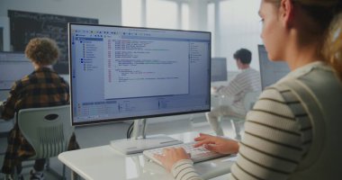 Enstitü Uygulamalı Kodlama Projesi 'ndeki kız. Dev Atölyesi 'nde, Genç Kadın Monitörde Daktilo Programı Kodu. Modern Eğitim, Bilgisayar Bilimi Öğrenimi, Gelecek Teknoloji Becerileri kavramları.
