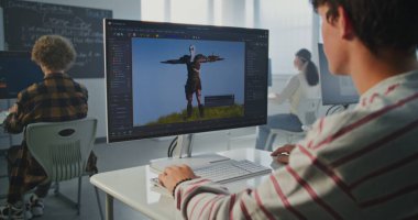 Sınıftaki Çocuk Bilgisayar 'da 3D Modelleme Projesi' nde çalışıyor. Genç adam animasyon yazılımıyla ekrana odaklandı. Yaratıcı Eğitim, Dijital Tasarım ve Geleceğin Meslekleri kavramı. Sabit Çekim.