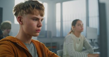 Orange Hoodie 'deki Erkek Öğrencinin Kapanışı Oyun Geliştirme Projesi Bilgisayar Yazma Çalışmaları. Genç adam modern programcılık okuyor. Gelecekteki bilişim kariyerleri, eğitim ve yaratıcılık. Portre.