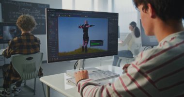 Sınıftaki Çocuk Bilgisayar 'da 3D Modelleme Projesi' nde çalışıyor. Genç adam animasyon yazılımıyla ekrana odaklandı. Yaratıcı Eğitim, Dijital Tasarım ve Geleceğin Meslekleri kavramı. Sabit Çekim.