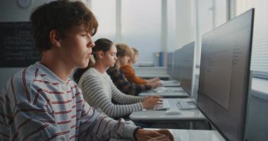 Çizgili Gömlekli Öğrencinin Kapanışı Yazma Koduna Yoğunlaşıyor. Oyun Tasarımı Projeleri üzerinde çalışan sınıf arkadaşlarıyla bilgisayar laboratuvarı. Modern eğitim ve gelecek bilişim becerileri kavramı. Sabit Çekim.