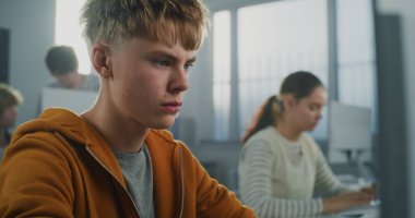 Orange Hoodie 'deki Erkek Öğrencinin Kapanışı Oyun Geliştirme Projesi Bilgisayar Yazma Çalışmaları. Genç adam modern programcılık okuyor. Gelecekteki bilişim kariyerleri, eğitim ve yaratıcılık. Portre.