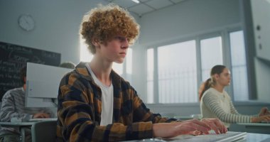 Kıvırcık Saçlı Yaklaş, Sunny Bilgisayar Laboratuvarındaki Yakışıklı Genç Adam Bilgisayar 'da İşine Odaklanıyor, Dikkatlice Video Oyunu için Kod Yazıyor. BTMM Eğitimi kavramı, Pratik Yetenekler. Portre.