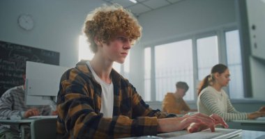 Kıvırcık Saçlı Yaklaş, Sunny Bilgisayar Laboratuvarındaki Yakışıklı Genç Adam Bilgisayar 'da İşine Odaklanıyor, Dikkatlice Video Oyunu için Kod Yazıyor. BTMM Eğitimi kavramı, Pratik Yetenekler. Portre.