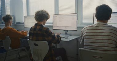 Programlama görevleri üzerinde çalışan bir grup genç üniversite öğrencisi. Parlak Bilgisayar Laboratuvarında Çocuklar Birlikte Kodlanıyor. Odaklanmış Öğrenciler Monitörler Üzerine Yazılım Geliştirme Üzerine Kod Yazıyor. Arka Görünüm.