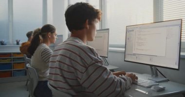 Parlak Sınıftaki Bilgisayar 'da Erkek Öğrenci Programı. IT Sınıfında Yazılım Çalışan ve Oyun Geliştirme Projeleri Yaratan Gençler Grubu. Takım çalışması, Teknoloji Eğitimi. Doli Vuruşu.