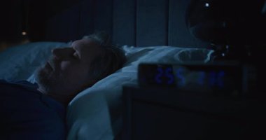 Yakın plan Orta yaşlı adam uykusuzluktan muzdarip. Gri saçlı adam, beyaz uyku maskesi takmış, yatakta uyanık yatıyor. Uykusuzluk, uykusuzluk, stres, gece anksiyetesiyle sessiz mücadele kavramını kabul et..