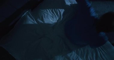 Yakışıklı, gri saçlı adam yatmaya hazırlanıyor. Olgun Adam Beyaz Yumuşak Yatağında Yatıyor ve İpek Uyku Maskesi Giyiyor. Uyku hijyeni, dinlenme ve iyileşme kavramı, sağlıklı uyku gereksinimi. Sabit Çekim.