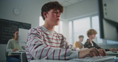 Kolej Sınıfında, Çizgili Kazaklı Kahverengi Saçlı Adam Oyun Geliştirme 'de Pratik Görev Yapıyor. Öğrenciler Klavyeye İsteyerek Yazıyor. Modern Eğitim, Dijital Disiplin Eğitimi kavramı.