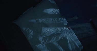 Mavi pijamalı beyaz saçlı adam yatak odasına girdi ve yatağa uzandı. Olgun Adam kendini beyaz battaniyeyle örtüyor ve tavana yorgun bakıyor. Uykusuzluk, uykusuzluk, akıl sağlığı. Üst Görünüm.