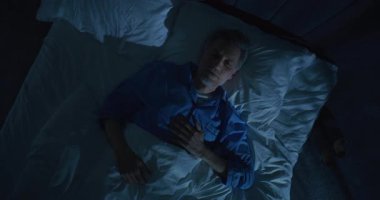 Gri Saçlı Olgun Adam Yatakta Yatar Uyuyamaz, Yaşlanma ve Yalnızlık Düşüncelerinde Kaybolur. Varoluşsal Korku, Anlamsal Kriz ve Uzun Uykusuz Gece 'deki Endişe kavramı. Üst Görünüm Döndürülüyor.