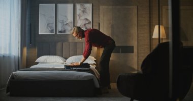 Kırmızı balıkçı yakalı gri saçlı adam ait olduğu eşyaları Stylish Otel odasındaki çantaya koyar. Gezgin Rutini, Seyahat Hazırlığı, İş Yaşamı, Anlık Düzenleme ve Odaklanma Konsepti.