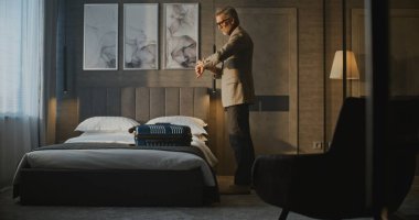 Yakışıklı Olgun Adam Bavula Ait Paketler, Ceketini Giyer ve Otel Odasından Çıkıyor. Seyahat rutini, seyahat hazırlığı, iş hayatı, iş seyahatleri, otel konaklama.