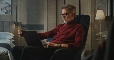 Şık İşadamı, Stylish Otel 'de dizüstü bilgisayar kullanıyor. Sıcak Tonlar, Sakin Işık, Odaklanma Atmosferi, Rahatlık ve Dijital Yaşam Tarzı. Concept Çevrimiçi İletişim, Uzaktan Çalışma, Küresel İş Hayatı.