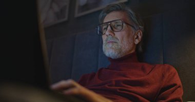 Tecrübeli Gezgin Gece Geç Saatlere Kadar Çalışıyor, Cozy Otel Yatağında Uzanıyor. Yatak Odasının Sakin Işıklandırması 'nda dizüstü bilgisayarda çalışan adam. Seyahat, Teknolojik Sofistike Çalışmalar ve Konsantrasyon Konsepti.