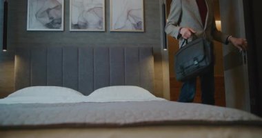 İş seyahatinden yorgun düşen adam yatağında dinleniyor. Otel odasındaki olgun adam Smartphone 'da haberlere çıkıyor. Otelde Yaşam Kavramı, İş Gezileri, Dijital Alışkanlıklar, Seyahatten Sonra Dinlenme. El bilgisayarı.