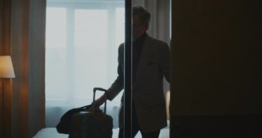 Gri Saçlı Zarif Olgun Adam Modern Otel Odasına Girdi. Adam Smartphone 'da 