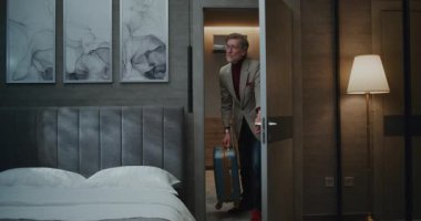 Olgun Avrupalı Adam, Sunny Otel 'de bavuluyla kalıyor. Gri Saçlı Adam, Odanın İçini Dikkatle İnceledi. Konsept, iş gezisi, otel hayatı, gezgin yaşam tarzı. Doli Vuruşu.