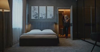 Tarz sahibi gri saçlı adam modern otel odasına yerleşti. İş adamı hemen cevapsız arama ve mesajları kontrol eder. Konsept İş Gezileri, Otel Kalışları, Modern İşlerin Dijital Düzenlemesi.