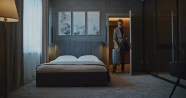 Yakışıklı Olgun Adam Modern Otel Odası 'na yerleşti. İş adamı ceketini çıkardı ve Yorgun bir şekilde yatağa uzandı. İş gezisi kavramı, otelde kalmak ve yolculuktan sonra dinlenmek. Sabit Çekim.